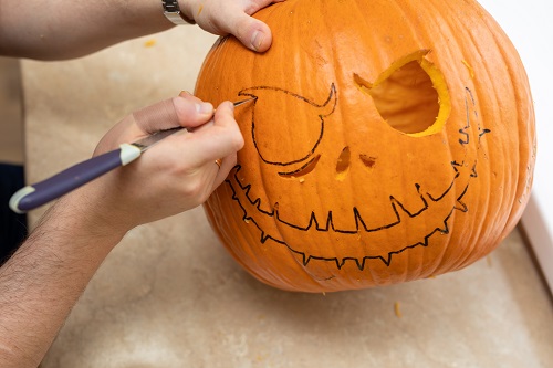 pessoa cortando um olho em uma abóbora de halloween