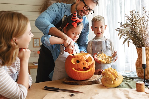 pai ajudando os seus filhos a decorar uma abóbora de halloween