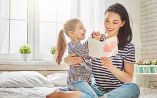 mãe com sua filha lendo um cartão de dia da mãe