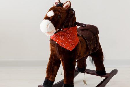 cavalo baloiço em forma de cavalo na cor marrom com um lenço na cor vermelha