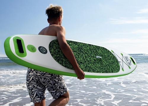 homem correndo para o mar com uma prancha de paddle surf