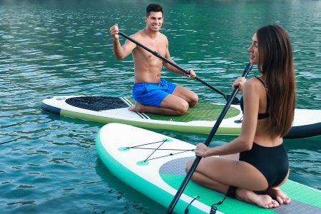 um homem e uma mulher em cima de uma prancha de paddle surf