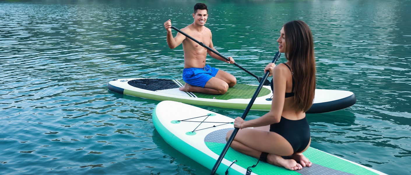 um homem e uma mulher em cima de uma prancha de paddle surf