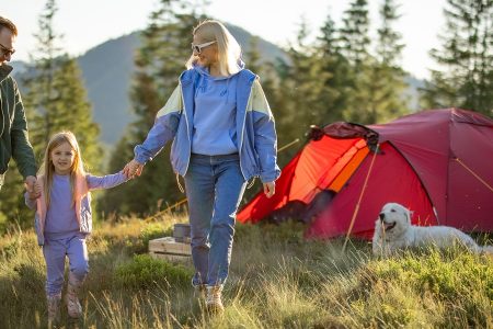 familia acampando no campo com uma tenda de campismo vermelha e laranja