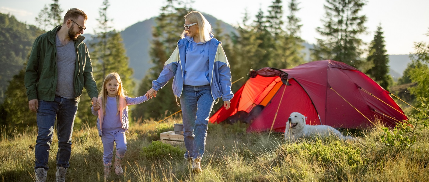 familia acampando no campo com uma tenda de campismo vermelha e laranja