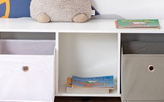 armário na cor branca com livros infantis e caixas de brinquedos