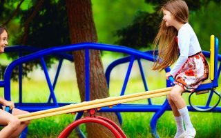 duas meninas em um baloio no parque