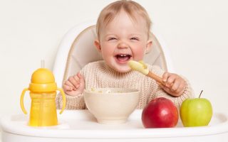 bebé comendo frutas em uma cadeira de refeição