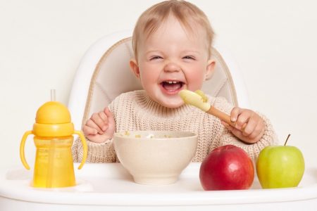 bebé comendo frutas em uma cadeira de refeição