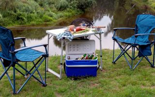 conjunto de mesa e cadeira de campismo perto de um lago com uma geleira