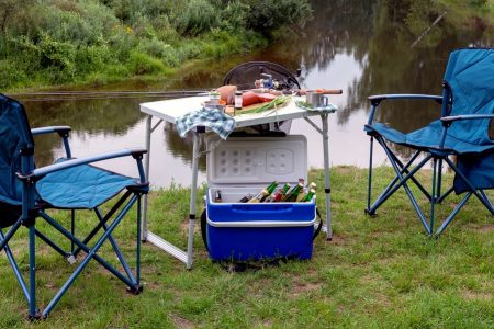 conjunto de mesa e cadeira de campismo perto de um lago com uma geleira