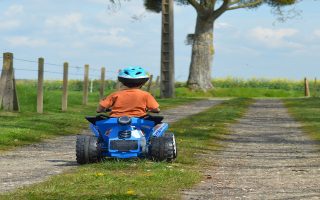 menino andando em um quadriciclo elétrico no bosque