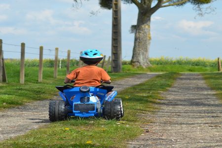 menino andando em um quadriciclo elétrico no bosque