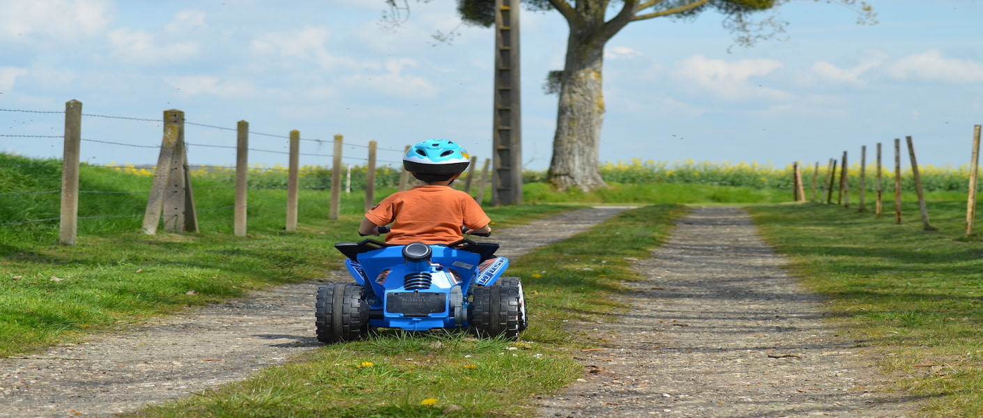 menino andando em um quadriciclo elétrico no bosque