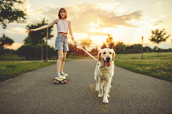 menina andando de skate com um cão