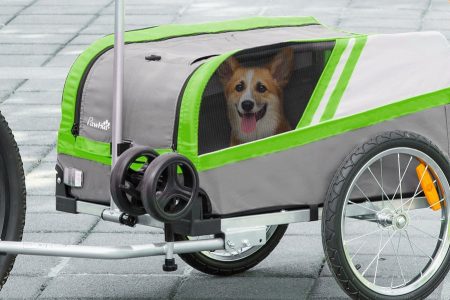 cão passeando dentro de um reboque para bicileta na cor cinza e verde