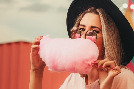 mulher comendo um algodão de açúcar cor de rosa