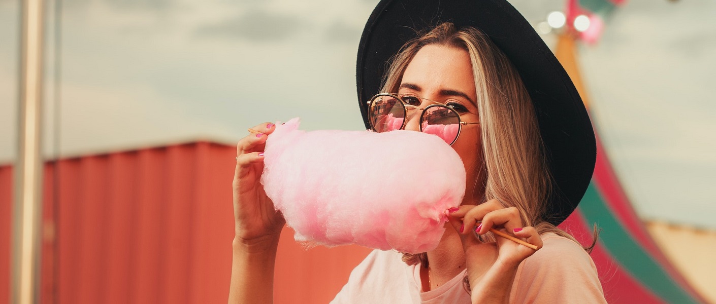 mulher comendo um algodão de açúcar cor de rosa