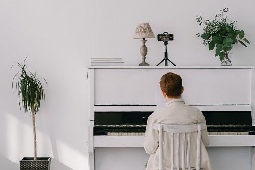 menino tocando um piano branco em casa 