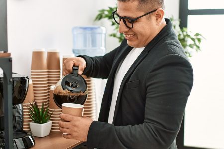 homem tomando café em uma estação de café no escritório