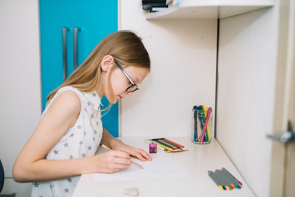 menina desenhando em uma secretária