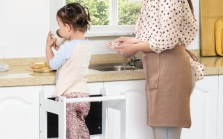 menina utilizando uma torre de apredizagem na cozinha