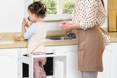 menina utilizando uma torre de apredizagem na cozinha