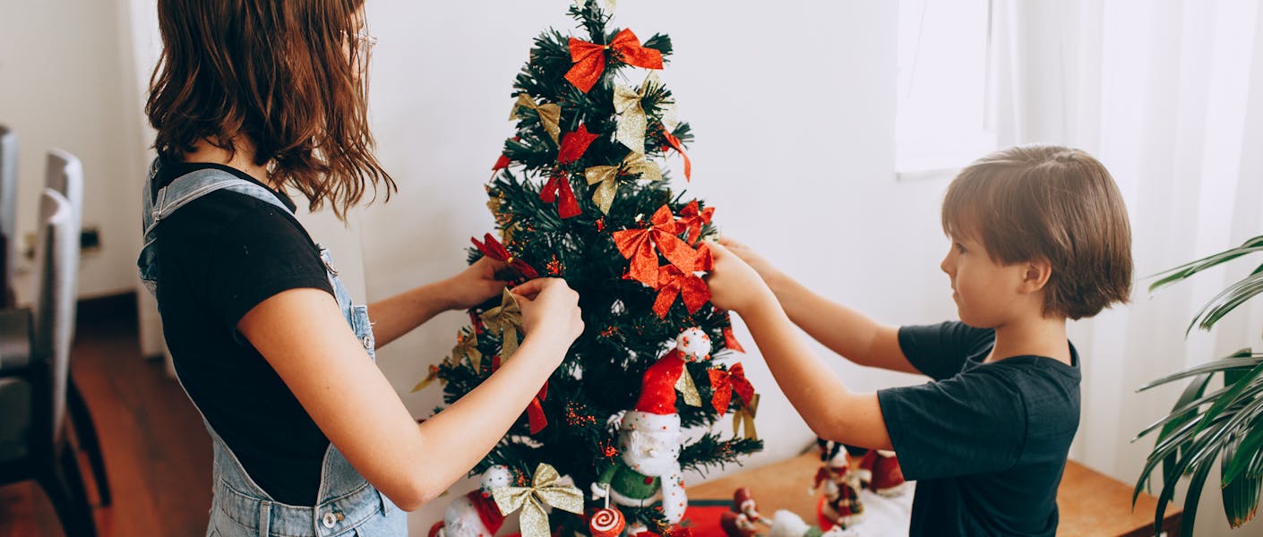 crianças decorando uma árvore de natal pequena